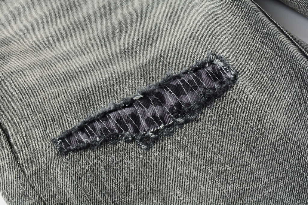 Jeans de mezclilla en tono gris lavado oscuro, acabado desgastado estilo vintage.