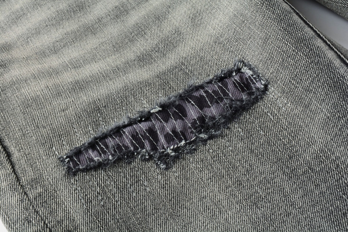 Jeans de mezclilla en tono gris lavado oscuro, acabado desgastado estilo vintage.
