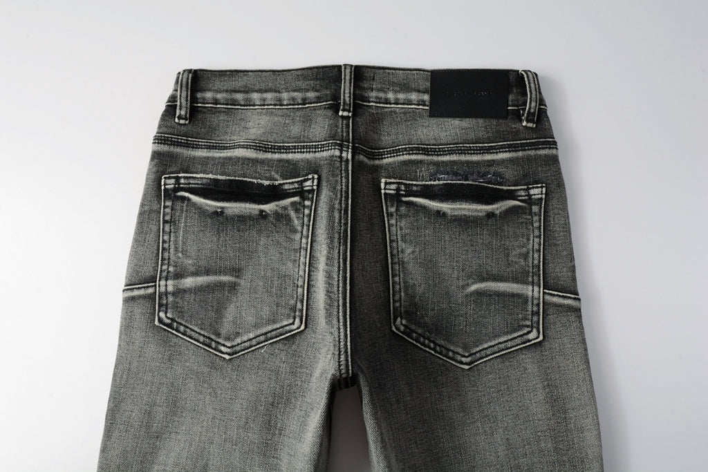 Jeans de mezclilla en tono gris lavado oscuro, acabado desgastado estilo vintage.