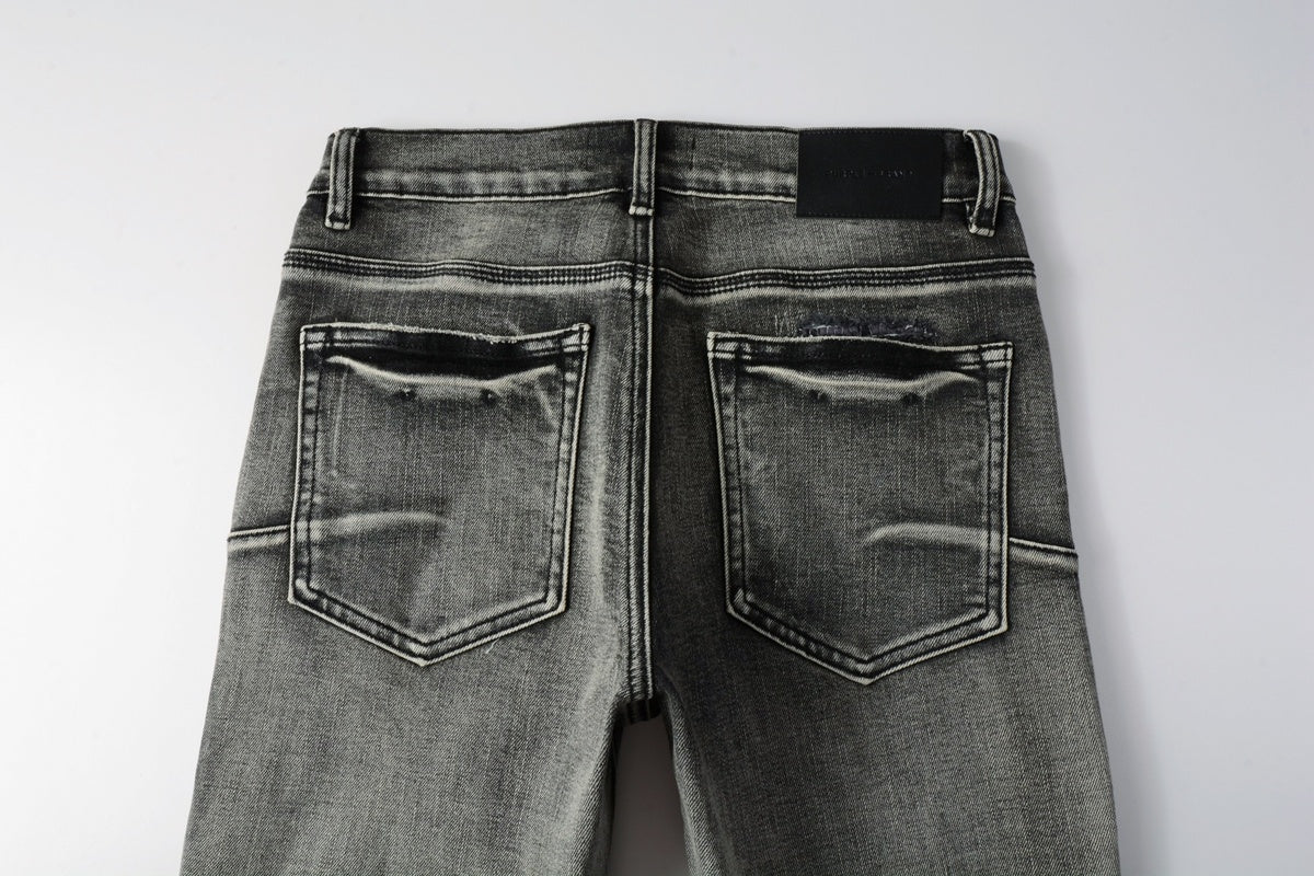 Jeans de mezclilla en tono gris lavado oscuro, acabado desgastado estilo vintage.