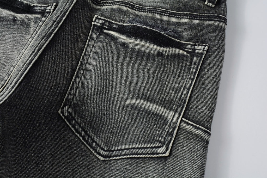 Jeans de mezclilla en tono gris lavado oscuro, acabado desgastado estilo vintage.