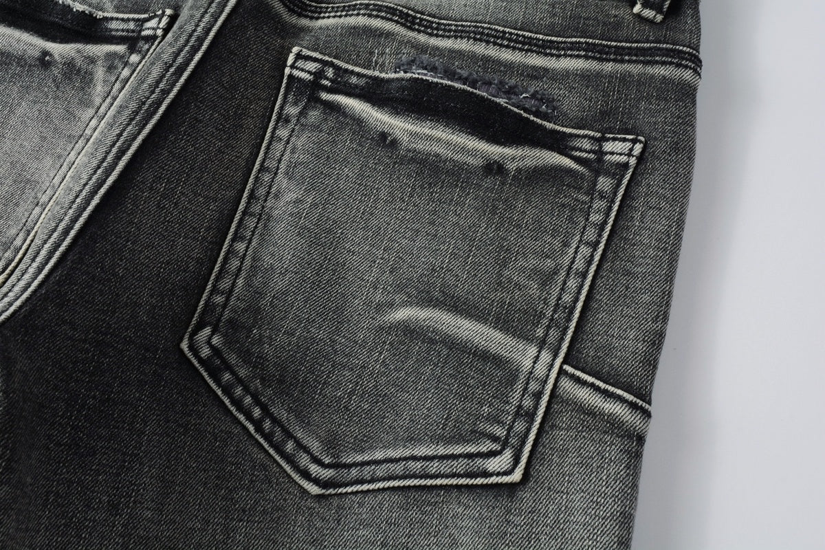Jeans de mezclilla en tono gris lavado oscuro, acabado desgastado estilo vintage.