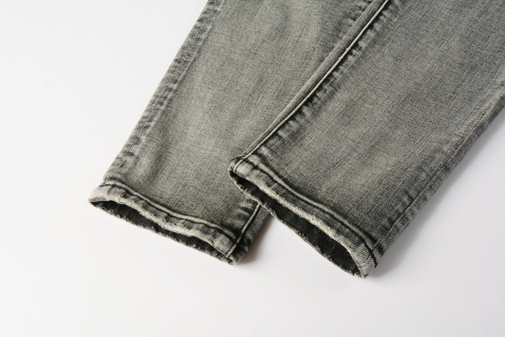Jeans de mezclilla en tono gris lavado oscuro, acabado desgastado estilo vintage.