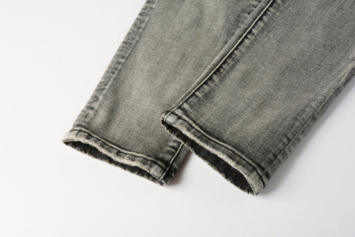 Jeans de mezclilla en tono gris lavado oscuro, acabado desgastado estilo vintage.