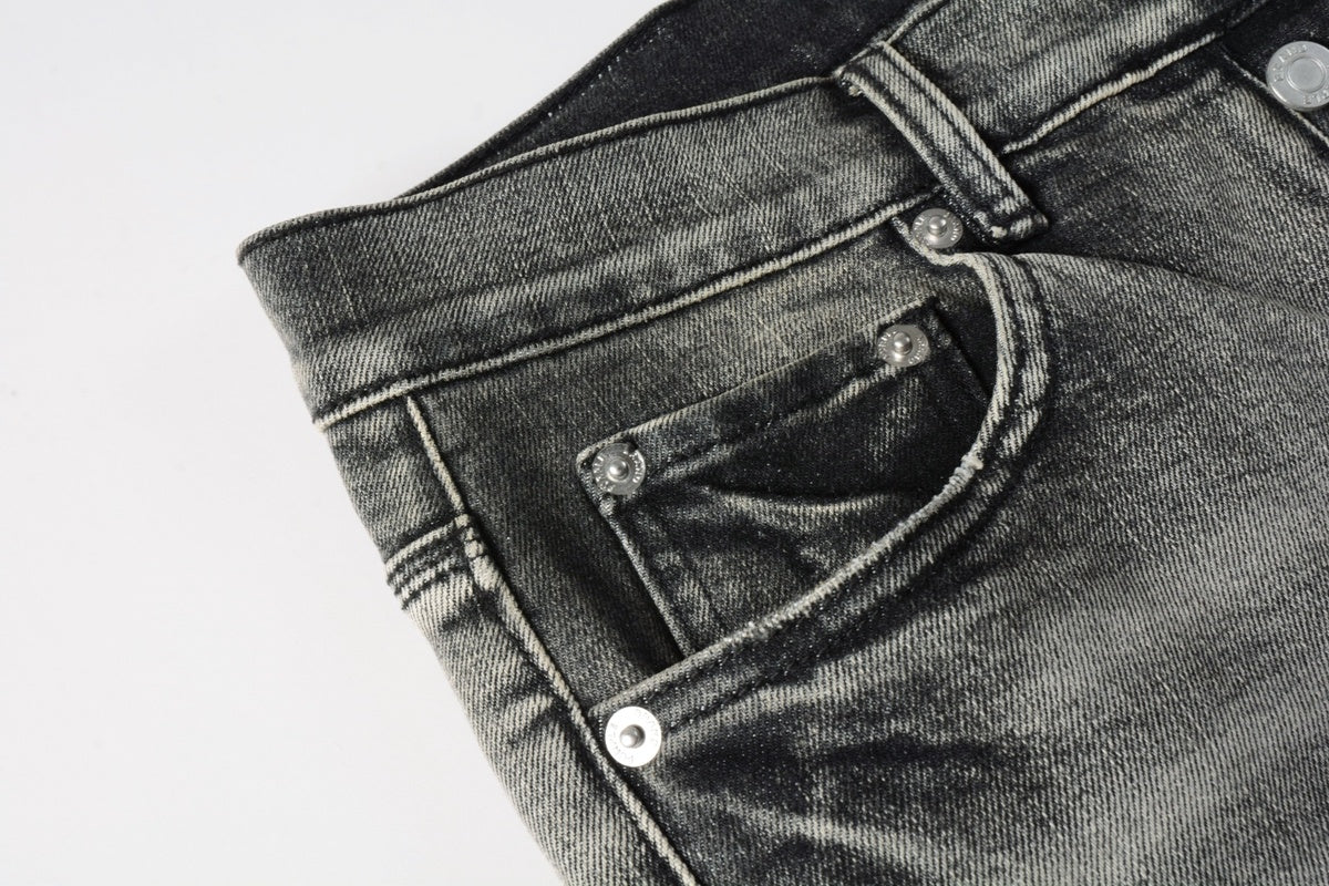 Jeans de mezclilla en tono gris lavado oscuro, acabado desgastado estilo vintage.