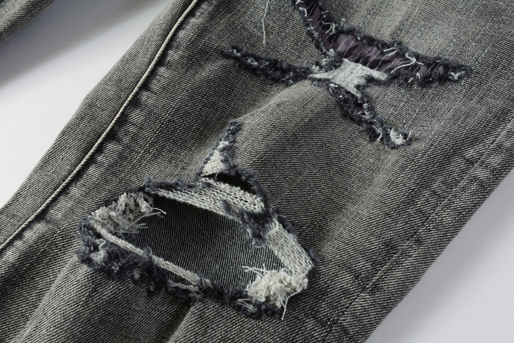 Jeans de mezclilla en tono gris lavado oscuro, acabado desgastado estilo vintage.