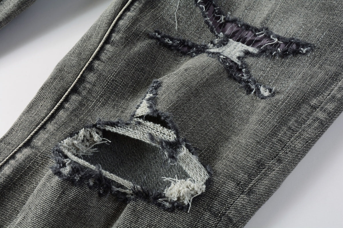 Jeans de mezclilla en tono gris lavado oscuro, acabado desgastado estilo vintage.