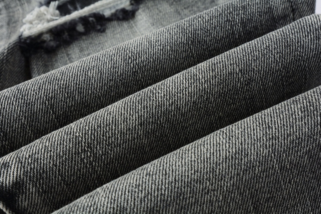 Jeans de mezclilla en tono gris lavado oscuro, acabado desgastado estilo vintage.