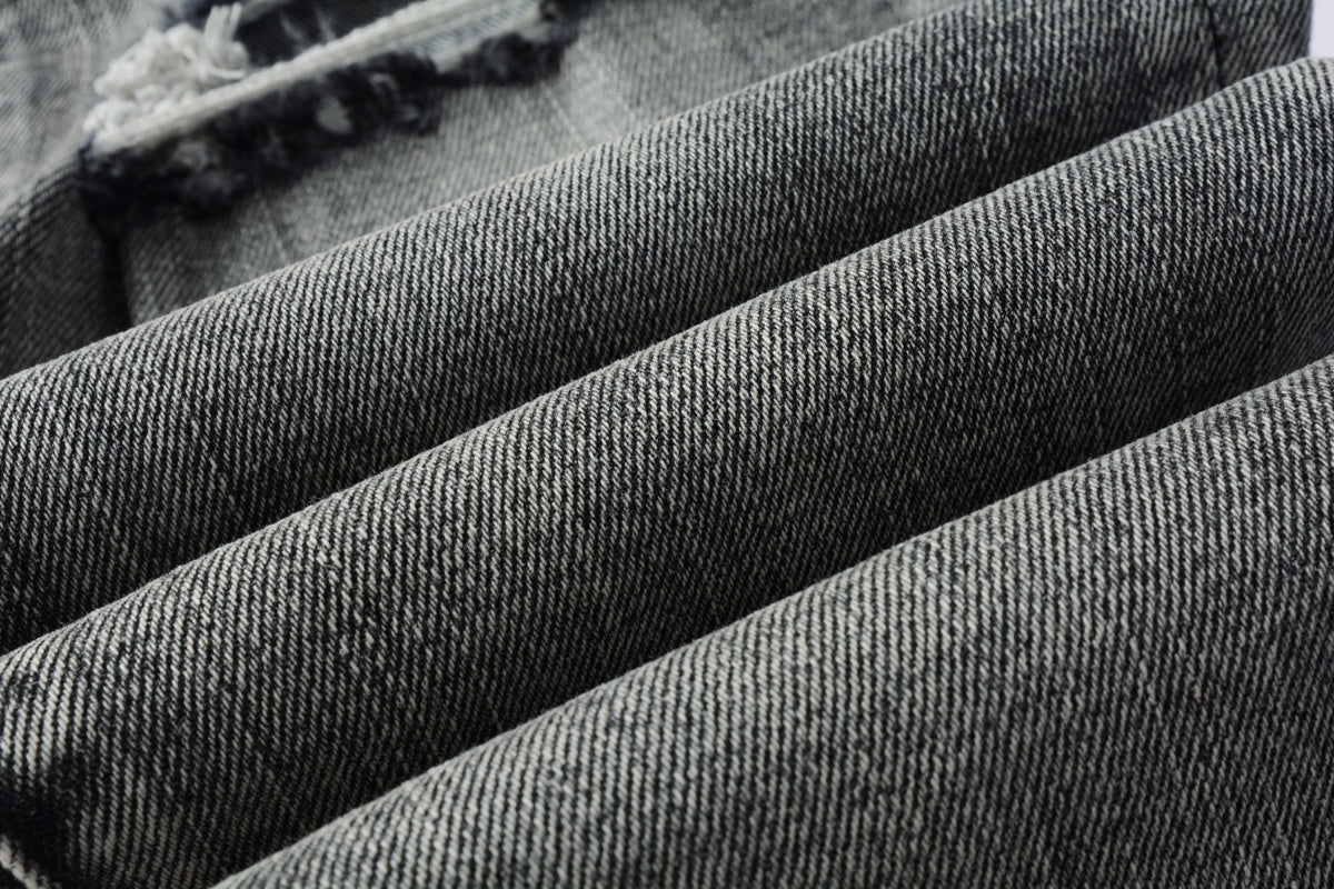 Jeans de mezclilla en tono gris lavado oscuro, acabado desgastado estilo vintage.