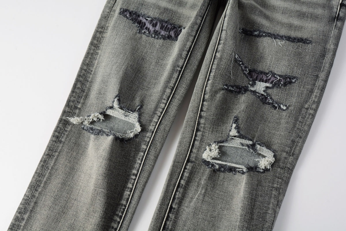 Jeans de mezclilla en tono gris lavado oscuro, acabado desgastado estilo vintage.
